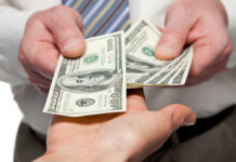 Two hands exchanging cash bills