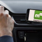 Driver using smartphone navigation app mounted on car dashboard