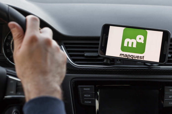 Driver using smartphone navigation app mounted on car dashboard