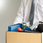 Brutal Cuts Hit Popular U.S. Food Company Person holding a box of personal office items.