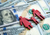 Red wooden family figures on hundred dollar bills