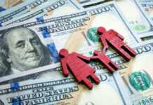 Red wooden family figures on hundred dollar bills