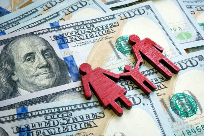 Red wooden family figures on hundred dollar bills