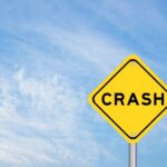 Yellow warning sign reading crash against blue sky