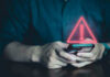 Person holding phone with warning symbol displayed.
