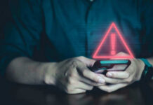 Person holding phone with warning symbol displayed.