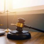 DA Drops Death – Stakes Stay Brutal Gavel and scales of justice on desk.