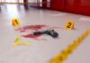 Teacher Shot In Shocking School Ambush Handgun on a blood-stained floor with evidence markers in a locker room