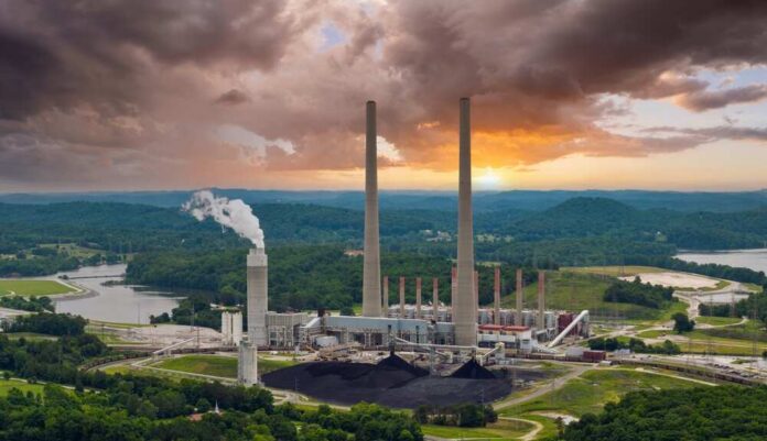 Coal-fired power plant with tall smokestacks at sunset