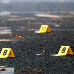 Doorbell Murder Stuns Community Yellow evidence markers labeled 8, 9, 10 on pavement.