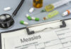 Medical supplies including a stethoscope, syringes, and medication related to measles