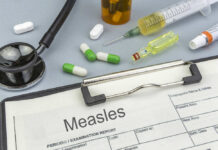 Medical supplies including a stethoscope, syringes, and medication related to measles