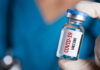 Person holding a vial labeled COVID-19 Vaccine.