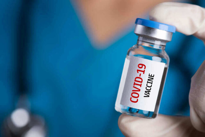 Person holding a vial labeled COVID-19 Vaccine.