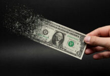 Dollar bill disintegrating while held by hand.