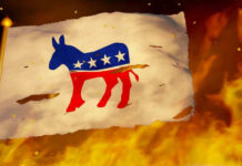 Torn Democratic flag burning amid flames and embers.