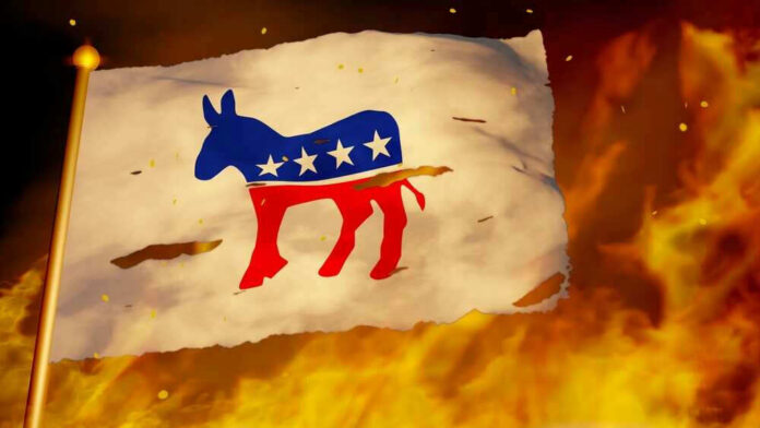 Torn Democratic flag burning amid flames and embers.