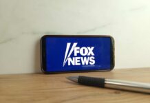 Smartphone displaying the Fox News logo on a wooden surface