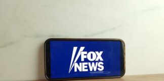 Smartphone displaying the Fox News logo on a wooden surface