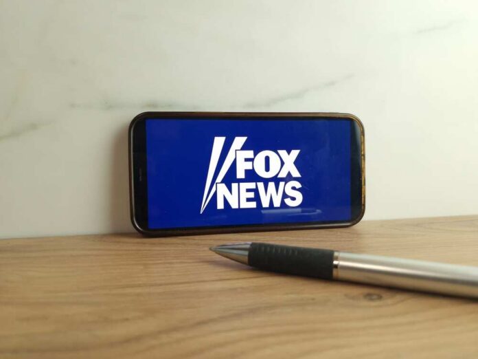 Smartphone displaying the Fox News logo on a wooden surface