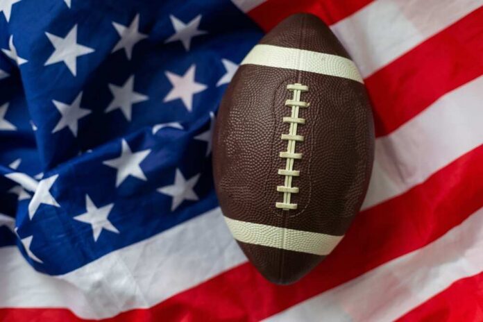 An American football resting on a background of the American flag