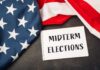 American flag and a notebook with 'MIDTERM ELECTIONS' written on it