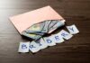 $100K AmEx Ask Explodes Envelope with cash and notes spelling bribery on wooden table