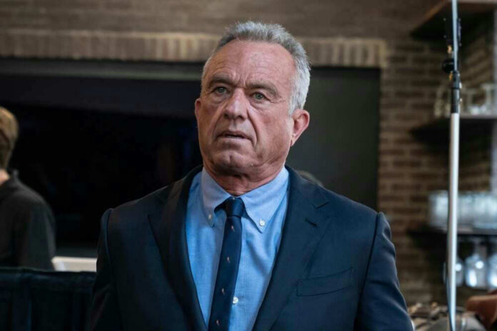 shutterstock_2456684687 Robert F. Kennedy Jr. in a navy suit and blue shirt indoors