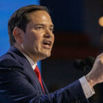 Marco Rubio speaking at a podium, pointing while addressing an audience