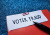 Paperclip holding paper labeled voter fraud marker