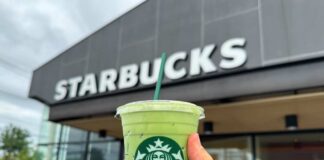 Hand holding a green matcha drink in front of a Starbucks store
