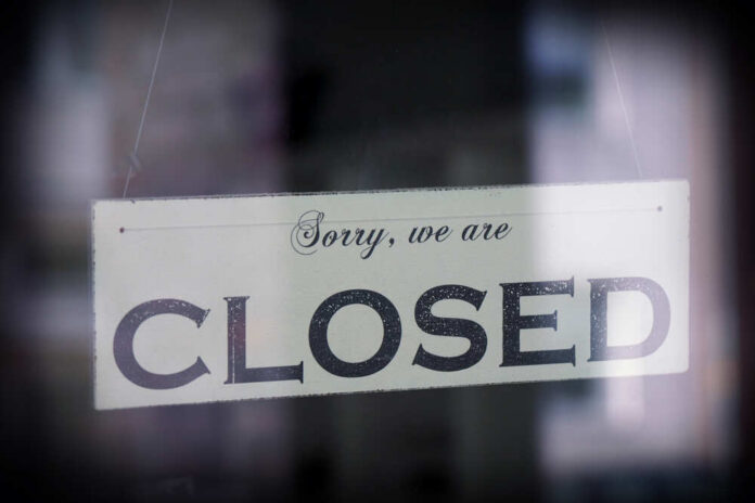 Sign,Saying,Sorry,We,Are,Closed,,Behind,Glass,With,Reflection, A sign hanging in a window that reads 'Sorry, we are CLOSED'